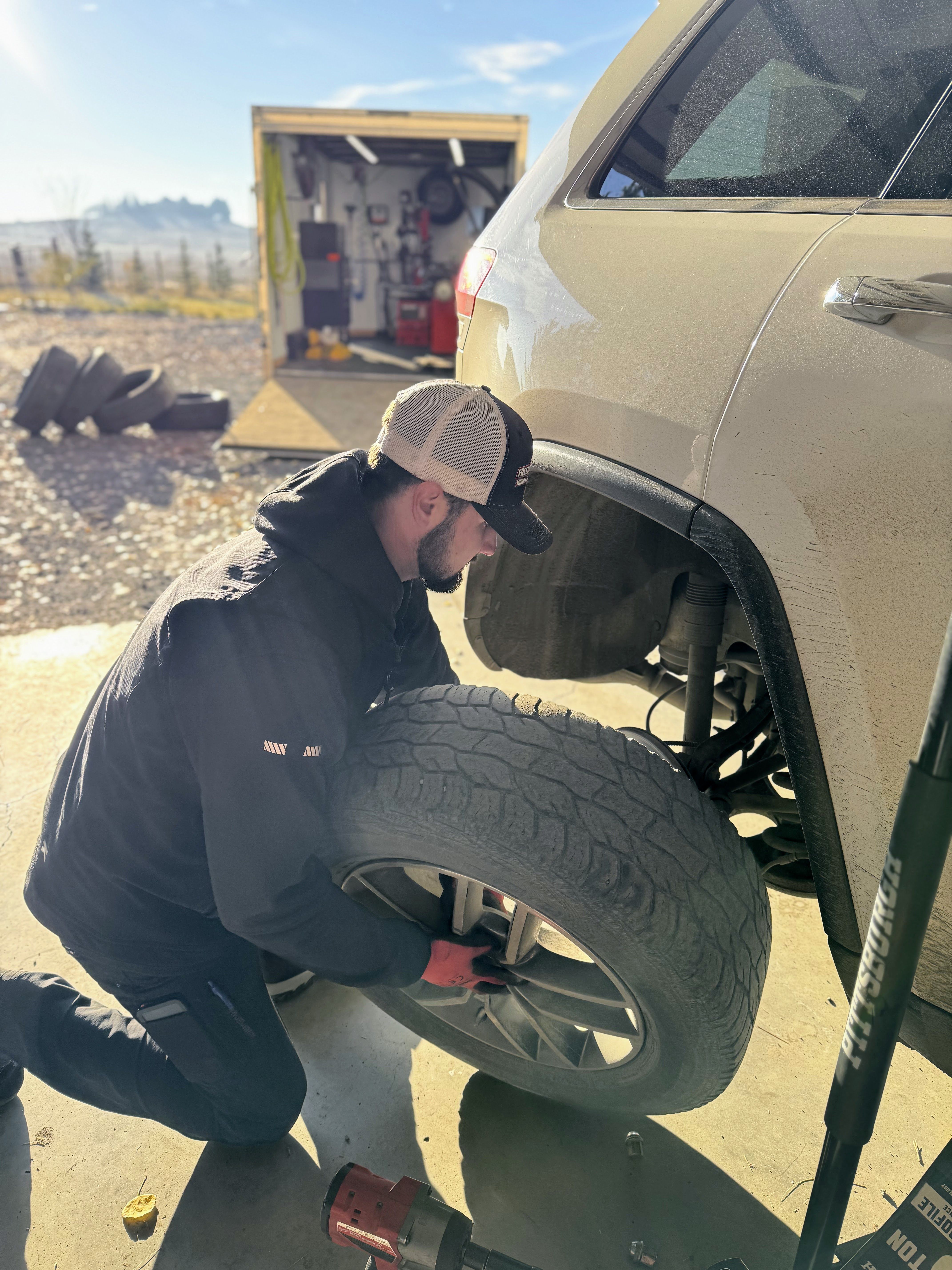 Freedom Tires technician installing tire on customer vehicle outdoors