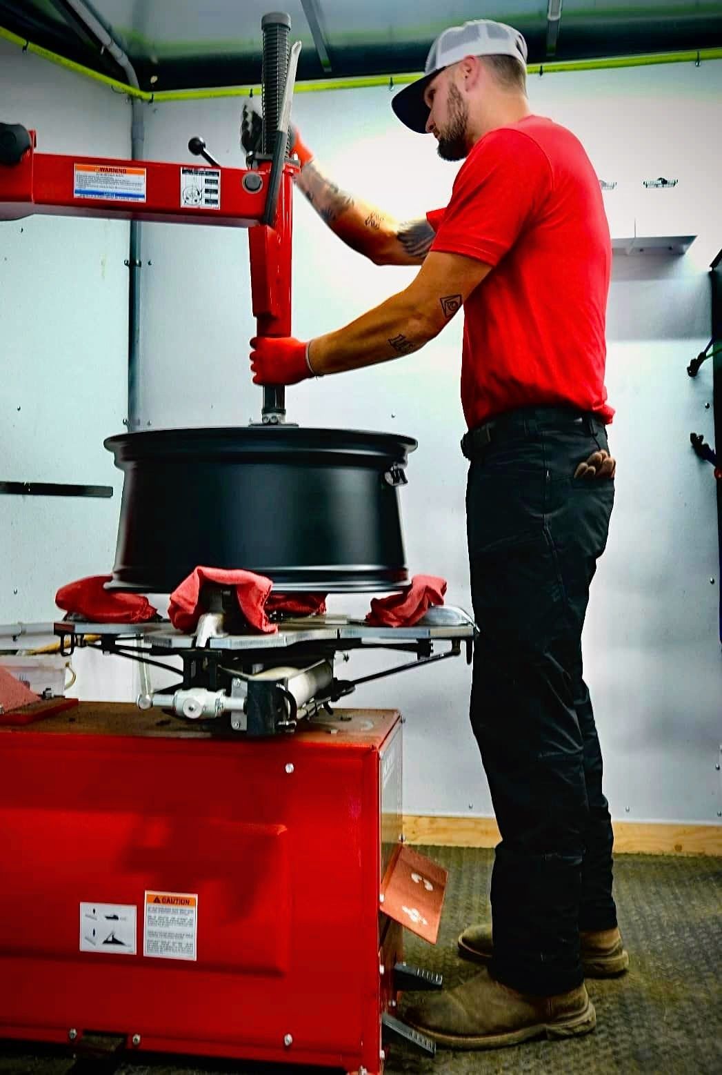 Freedom Tires operator using tire changer machine inside mobile trailer